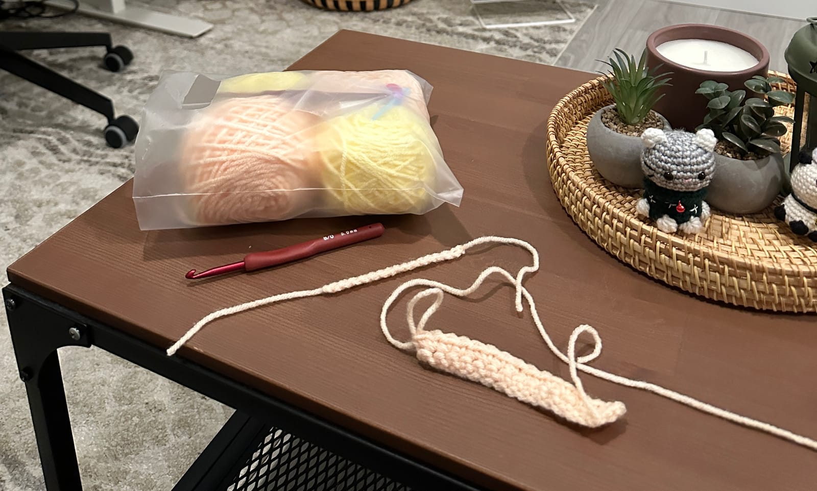 Cream-coloured yarn and a wooden crochet hook resting on a soft neutral background
