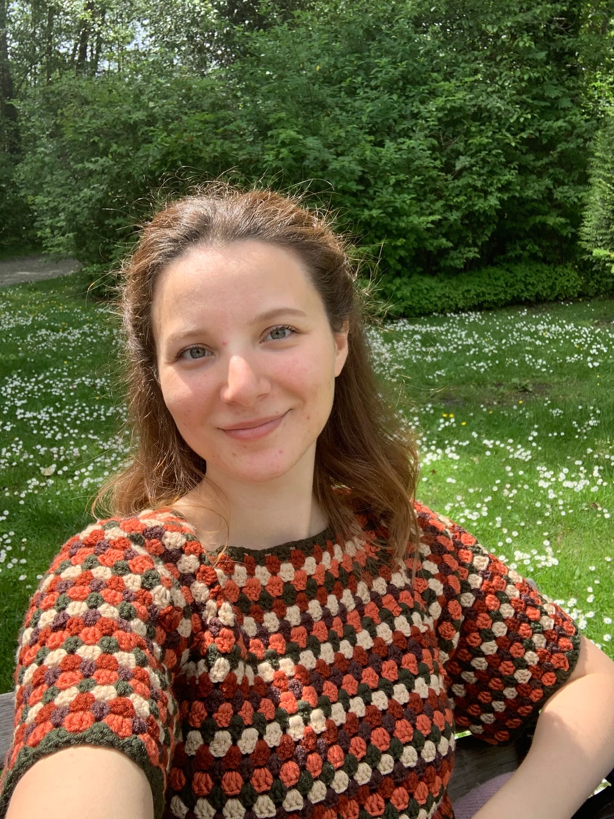 Neslihan, founder of Delightie Studio, smiling outdoors in a crochet top